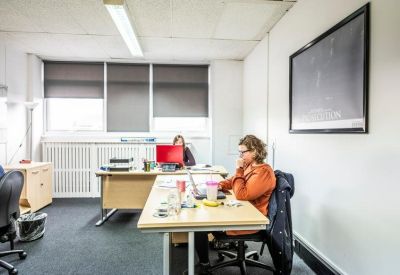 Shared office space featuring individual desks and natural light from large windows.