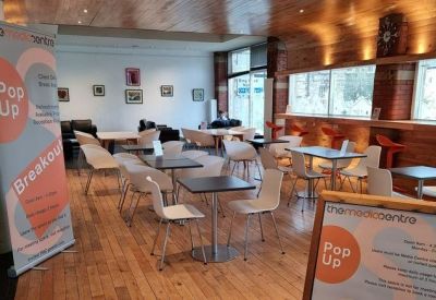 Vibrant communal breakout area with wooden floors and cafe-style seating.