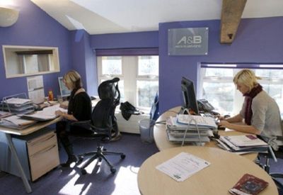 A shared office room with purple accent walls and workstations.