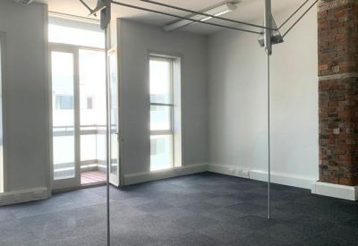 Spacious private office with large windows and an exposed brick pillar.