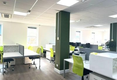 Open-plan office space with white desks, lime green chairs, and a central green pillar.