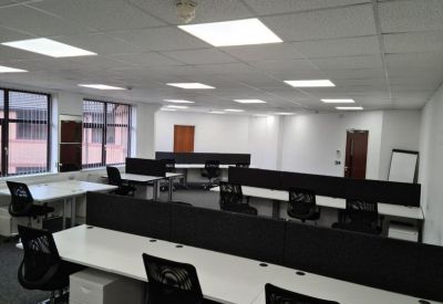 Spacious open-plan workspace featuring rows of white desks with black privacy dividers.