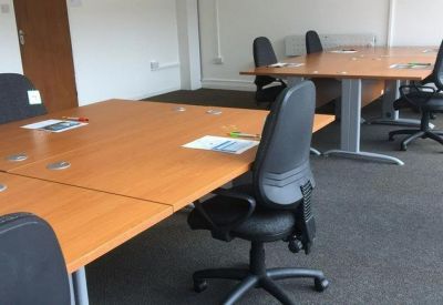 Spacious workstation area with wooden desks and black ergonomic chairs.