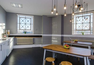 Spacious communal dining area with industrial bulb lighting and large windows.