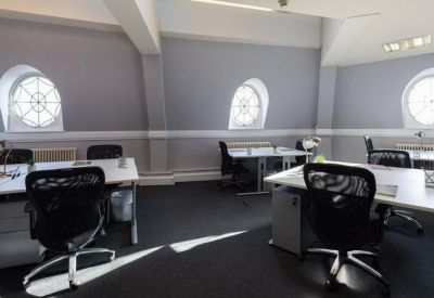 Open-plan office space with black ergonomic chairs and distinctive circular windows.