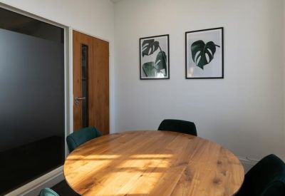 Small private meeting room with a round wooden table and botanical wall art.