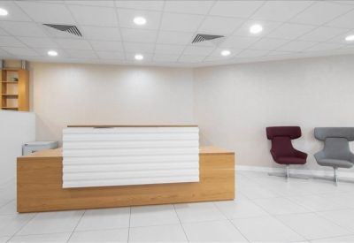 Bright reception area featuring a wood-fronted desk and designer wingback chairs.