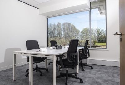 Bright four-person office suite with large windows and black mesh chairs.