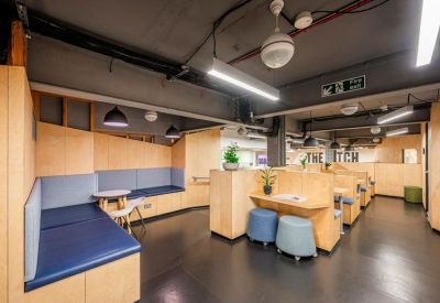 Communal breakout space featuring blue cushioned booths and natural wood panelling.