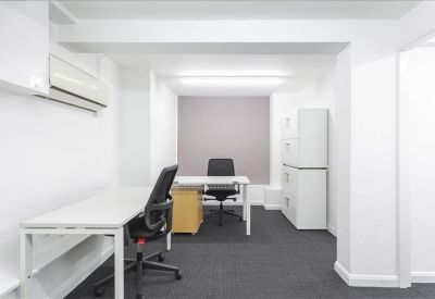 A modern white office suite with desks, ergonomic chairs, and grey carpeting.