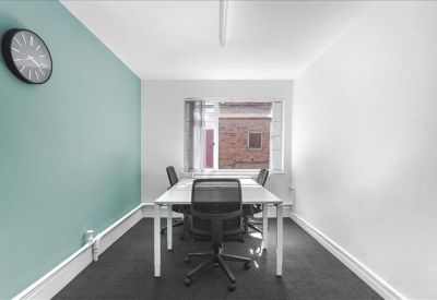 Meeting room featuring a teal accent wall, clock, and white table with four chairs.