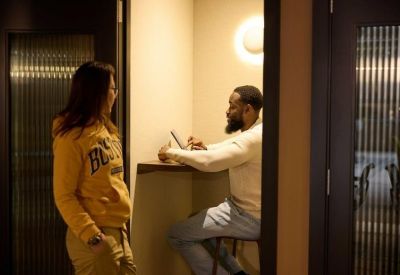 Two people collaborating in a private phone booth or small workspace with a light-filled wall.