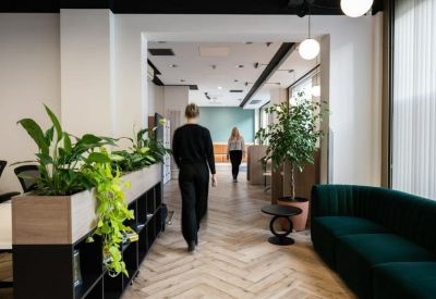 Modern office hallway with herringbone flooring and vibrant green plants.