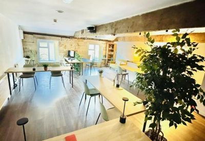 Interior view of The Saw Mill showing open-plan desks, rustic timber beams, and indoor plants.