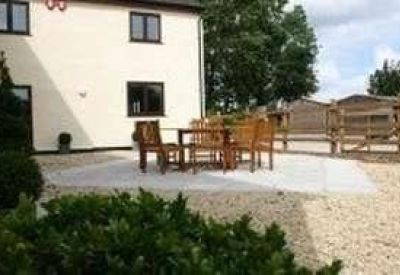 Outdoor patio area with wooden dining furniture on a light gravel base.