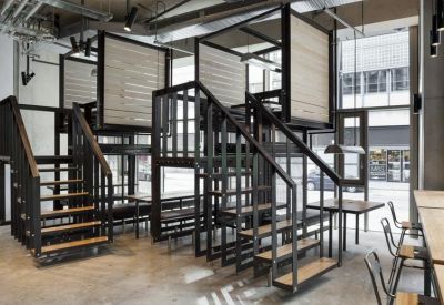 Unique multi-level internal structure with black metal stairs leading to elevated wooden meeting pods.