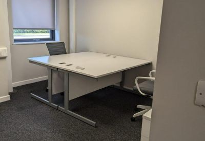 Private internal office with a large white corner desk and grey carpet.