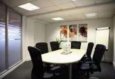 Modern meeting room with an oval white table, black mesh chairs, and abstract wall art.
