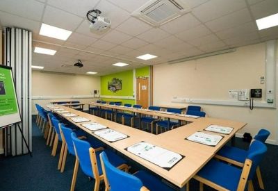 Spacious meeting room with blue chairs and a U-shaped table layout.