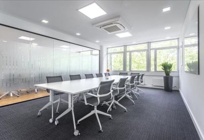 Modern conference room featuring a white table, grey chairs, and a glass partition.