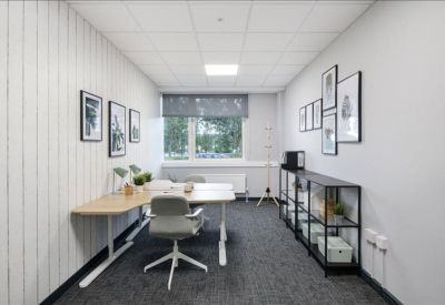 Private office with a wood-tone corner desk, grey chair, and framed art on a vertical-slat wall.