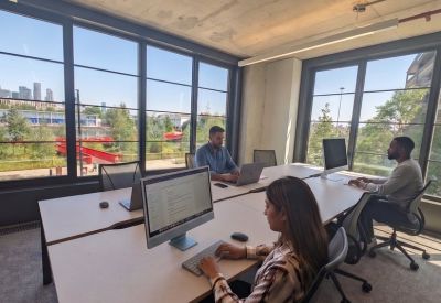 Bright open-plan office space with large windows and modern workstations.