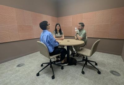 Small three-person breakout meeting room with neutral tones and acoustic wall panels.