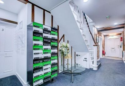 Bright reception area with white stairs, mailboxes, and a glass table.