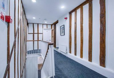 First-floor landing with historic timber wall studs and blue carpeting.
