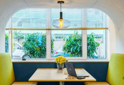Private meeting booth with yellow seating and a large window overlooking lush green trees.