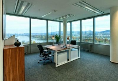 Sunlit private office with two desks and expansive river views.