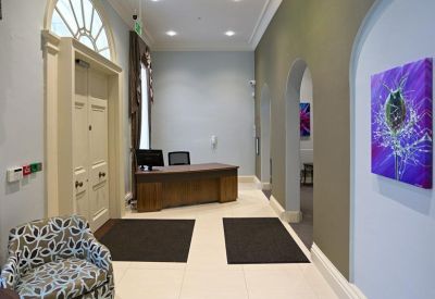 Bright reception area with a wooden front desk, arched doorways, and colorful abstract artwork.