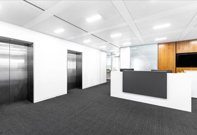 Modern reception area with a white and grey desk and two stainless steel elevator doors.