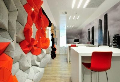 Creative breakout area with a 3D geometric wall in grey and red.