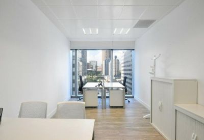 Private windowed office with two desks and a view of the city skyline.