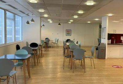 Spacious communal breakout area with modern dining tables and chairs.