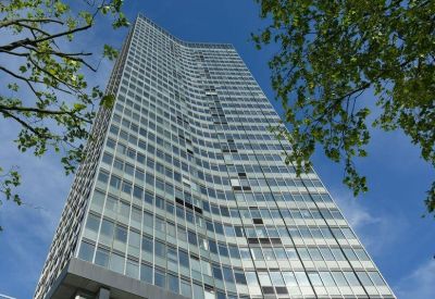 A low angle view of the glass-facade Millbank Tower against a bright blue sky.