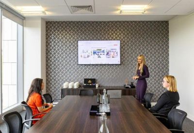 Professional boardroom with a dark wood table and a wall-mounted presentation screen.
