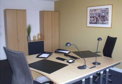 Private office with two desks, task lamps, and wooden storage cabinets.