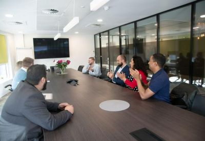 Modern conference room with a large dark wood table, black chairs, and glass partition walls.