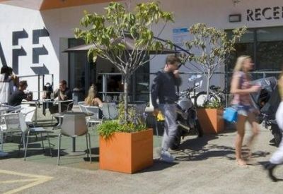 Lively outdoor cafe seating area and main reception entrance under a clear sky.