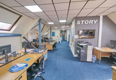 Modern attic office space with sloped ceilings and a Story wall graphic.