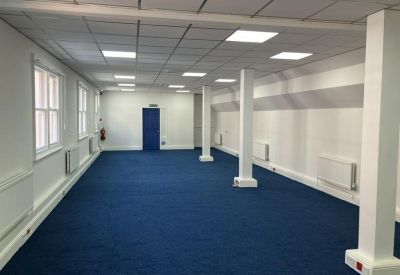 Spacious, open-plan office suite with white support pillars and blue carpeting.