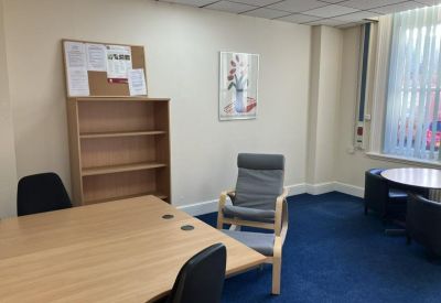 Private office room featuring a wooden bookshelf and comfortable grey armchair.