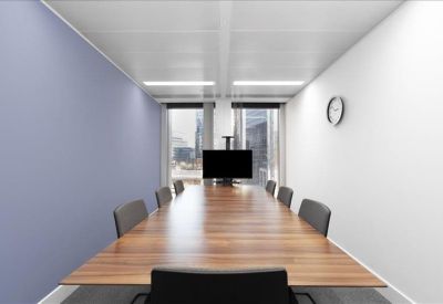 Sleek meeting room featuring a long wooden table, grey chairs, and a blue accent wall.