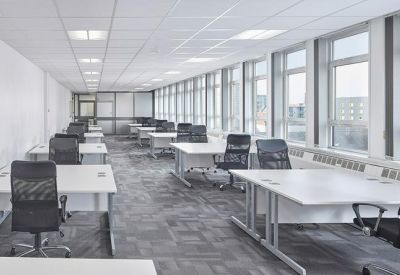 Large open-plan office workspace with rows of white desks and ergonomic chairs.