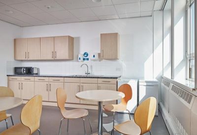 Communal kitchen and break area with wooden cabinetry and circular dining tables.