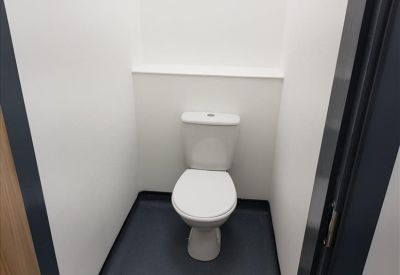 Clean and simple toilet room with white walls and a dark floor.