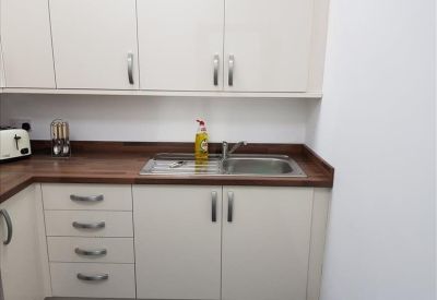 Kitchenette area featuring a stainless steel sink and under-counter storage cabinets.