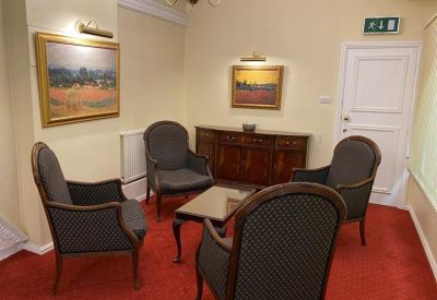 Comfortable lounge area with four grey armchairs arranged around a coffee table.